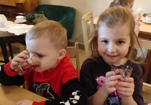 Dzieci przy stolikach piją kompot.