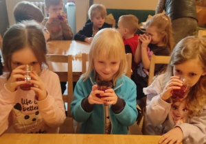 Dziewczynki przy stoliku piją kompot.