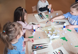 Dzieci wyklejają kolorowymi kółkami palemki