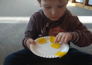 Brunon układa kawałki żółtej bibuły na talerzyku