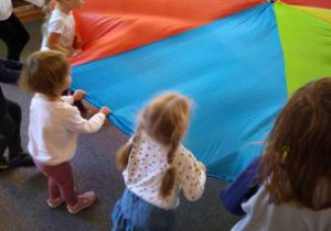 Dzieci falują chustą, na której umieszczony jest balon
