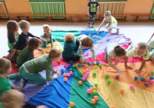 Dzieci bawią się na chuście animacyjnej kolorowymi piłeczkami