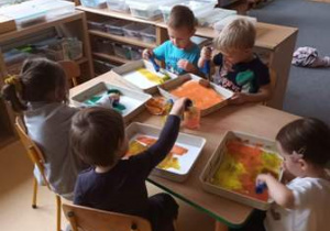 Dzieci malują farbami tło do pracy plastycznej "Muchomor"