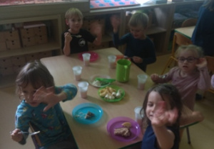 Dzieci siedzą przy stoliku podczas urodzinowego poczęstunku
