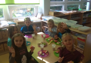 Dzieci siedzą przy stolikach podczas poczęstunku urodzinowego
