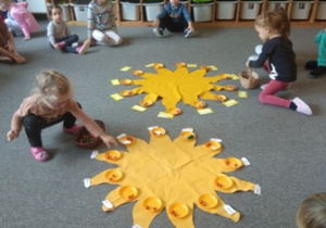 Dzieci na słoneczkach urodzinowych układają koraliki symbolizujace miesiące życia Filipka i Zuzi