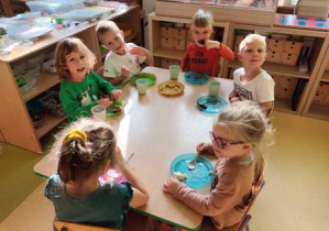 Dzieci siedzą przy stoliku podczas urodzinowego poczęstunku.