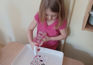 Dziewczynka spryskuje wodą serwetkę, którą ozdobiła mazakami