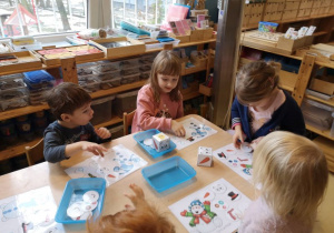 Dzieci układają na planszach do gry elementy wyrzucone na kostce
