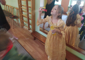 Dziewczynka w stroju księżniczki puszcza bańki mydlane