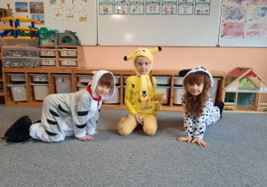 dziewczynka przebrana za Pikachu i dziewczynki przebrane za pieska i kotka pozują do zdjęcia