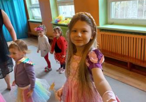 Amelia w stroju księżniczki, w tle widać tańczące dziewczynki