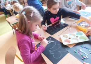 Dzieci przy stoliku wyklejają napis 2023 kolorowymi kwadracikami ozdobnymi