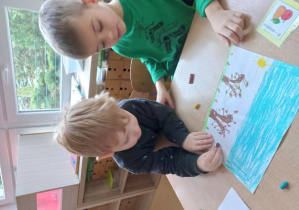 Filip i Brunon rysują kredkami pastelowymi ilustrację do miesiąca września