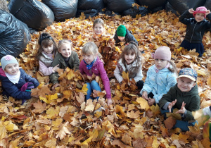 dzieci siedzą w stercie liści i pozują do zdjęcia
