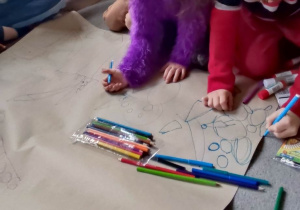 Dzieci rysują na dużym arkuszu papieru