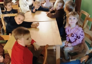 Dzieci siedzą przy stolikach i czekają na przedstawienie teatralne