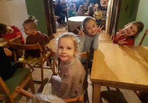 Dzieci siedzą przy stolikach w oczekiwaniu na przedstawienie