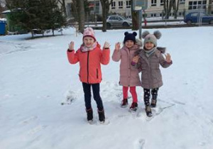 Trzy dziewczynki pozują do zdjęcia w czasie zimowej aury