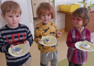 Troje dzieci młodszych stoi i prezentuje efekty swoich działań z masą solną
