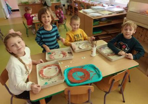 Dzieci przy stoliku podczas wykonywania tematycznej pracy plastycznej związanej z obchodzeniem "Tłustego czwartku"