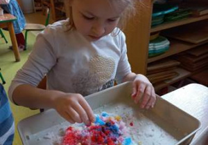 Dziewczyna przy użyciu pipety barwi rozwodnioną wodą sztuczny śnieg