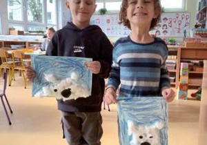 Chłopcy trzymają w dłoniach swoje prace plastyczne przedstawiające niedźwiedzia polanego wyklejonego za pomocą waty