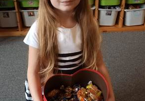 Jubilatka trzyma w dłoniach pudełko w kształcie serca wypełnione cukierkami dla kolegów i koleżanek z grupy