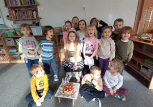 Grupa dzieci pozuje do zdjęcia z jubilatką oraz tortem urodzinowym