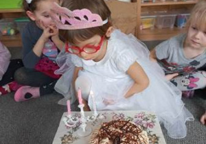 Jagódka zdmuchuje świeczki z urodzinowego tortu