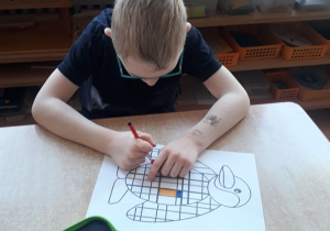 chłopiec koloruje obrazek inspirowany twórczością Pieta Mondriana