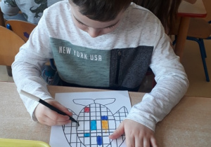 chłopiec koloruje obrazek inspirowany twórczością Pieta Mondriana