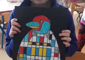 dziewczynka prezentuje gotową pracę pingwina inspirowaną twórczością Pieta Mondriana Mondriana