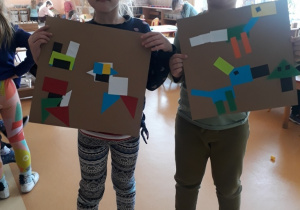 dziewczynka i chłopiec prezentują swoje prace z figur geometrycznych