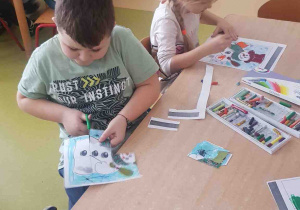 Dzieci przecinają nożyczkami na mniejsze części rysunek bałwana