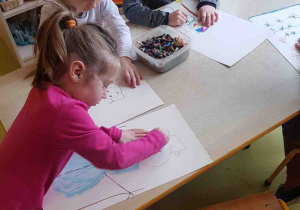 Dzieci rysują przy stole bałwanka wg instrukcji z wiersza