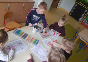 Dzieci kolorują mazakami kartę pracy z wizerunkiem serca