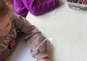 Dzieci wypełniają walentynkową kartę pracy ze szlaczkami w kształcie serca