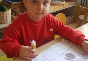 Chłopiec przykleja emblematy pączka na karcie sudoku