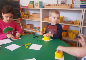 Dzieci odrysowują kształt koła potrzebny do wykonania bałwana