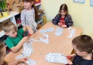 Dzieci w trakcie gry matematycznej polegającej na rzucaniu kostką i odcinaniu odpowiedniej cyfry