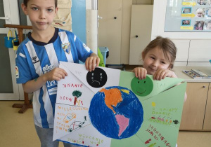 Chłopiec i dziewczynka prezentują wykonany przez siebie plakat