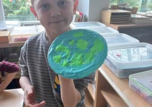 Maciej prezentuje wykonaną przez siebie "Ziemię" malowaną rosnącymi farbami w kolorze zielonym oraz niebieskim