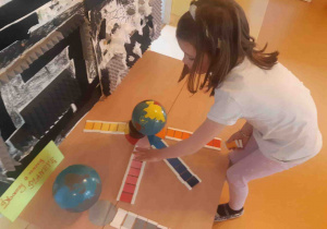 Dziewczynka układa barwne płytki wokół globusa z kontynentami