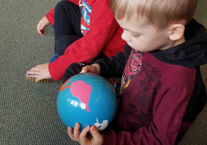 Dzieci oglądają globus z kolorowymi kontynentami
