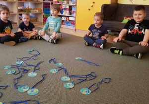 Dzieci siedzą w kręgu wokół medali