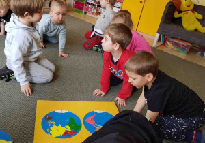 Chłopcy układają puzzle z drewnianymi kontynentami