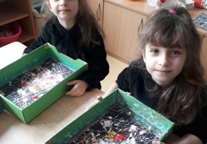 dziewczynki pozują do zdjęcia z pudełkami ze szklanymi kulkami