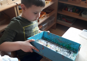 dzieci poruszają pudełkiem z kulkami umoczonymi w farbie
