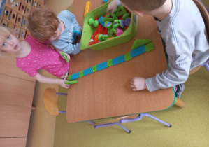 Dzieci konstruują z klocków tory przeszkód dla piórek